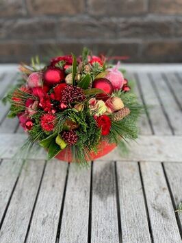 kerstbloemstuk 12 rond compact gestoken in rode tinten met kerstdecoratie